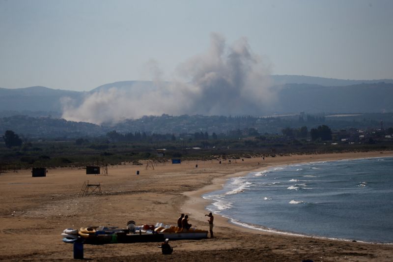 © Reuters. People spend time at a beach as smoke billows in the background over southern Lebanon following an Israeli strike, amid ongoing cross-border hostilities between Hezbollah and Israeli forces, as seen from Tyre, Lebanon September 26, 2024. REUTERS/Amr Abdallah Dalsh