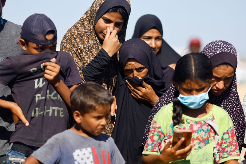 &copy; Reuters. People cover their faces as others bury in a mass grave unidentified bodies of Palestinians killed in Israel's military offensive, after they were handed over by Israel, amid the Israel-Hamas conflict, in Khan Younis in the southern Gaza Strip September 2