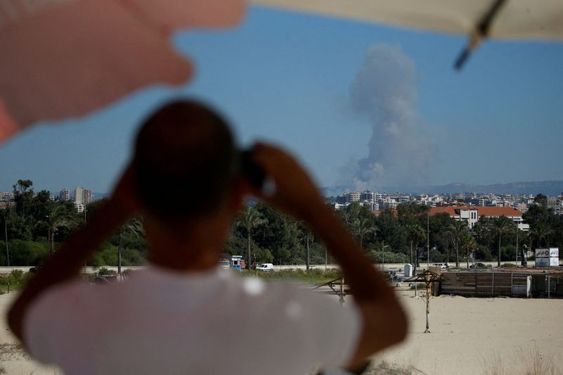 © Reuters. FILE PHOTO: A man watches as smoke billows over southern Lebanon following an Israeli strike, amid ongoing cross-border hostilities between Hezbollah and Israeli forces, as seen from Tyre, Lebanon September 26, 2024. REUTERS/Amr Abdallah Dalsh/File Photo