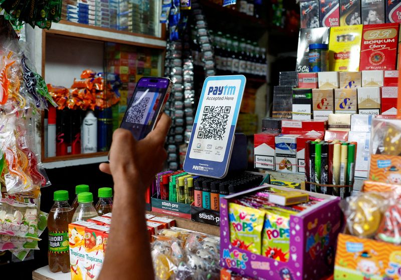 © Reuters. FILE PHOTO: A man uses his phone to scan a QR code of the digital payment app Paytm after purchasing a cold beverage at a shop in Kolkata, India on July 9, 2024. REUTERS/Sahiba Chawdhary/File Photo