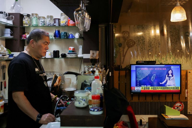 &copy; Reuters. FILE PHOTO: A person stands in a cafe as a news broadcast shows China announcing new military drills around Taiwan, in Keelung, Taiwan, May 23, 2024. REUTERS/Ann Wang/File Photo