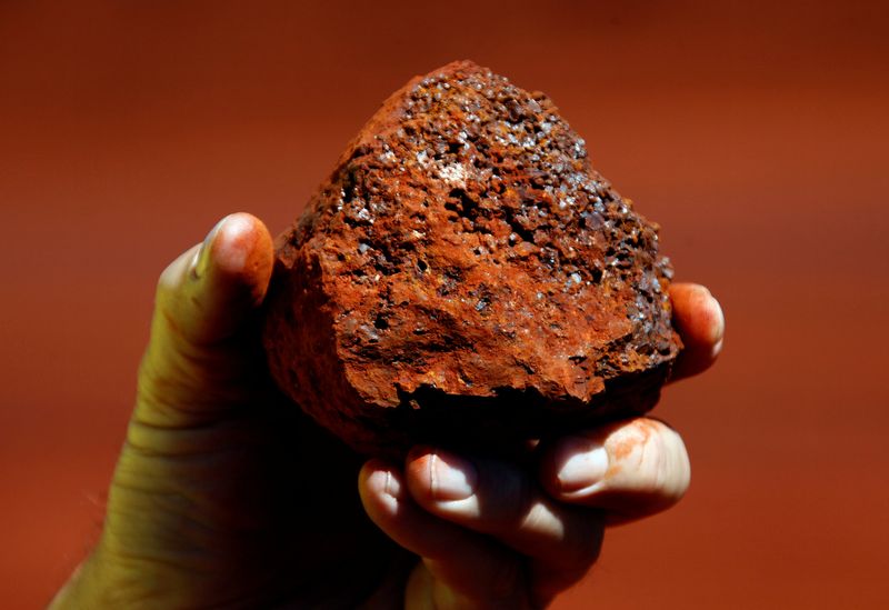 © Reuters. FILE PHOTO: A miner holds a lump of iron ore at a mine located in the Pilbara region of Western Australia, December 2, 2013.   REUTERS/David Gray/File photo