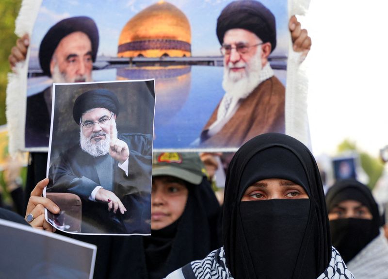 © Reuters. A woman holds a picture of Lebanon's Hezbollah Chief Hassan Nasrallah who was killed by an Israeli airstrike in Beirut, during a symbolic funeral in Basra, Iraq, September 29, 2024. REUTERS/Essam al-Sudani