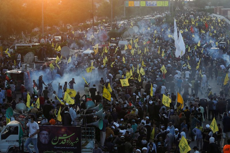 © Reuters. Pakistani Shi'ite Muslims carry flags as they protest the killing of Lebanon's Hezbollah leader Sayyed Hassan Nasrallah in an Israeli air strike in Beirut, amid tear gas smoke fired by police to disperse them as they march towards the U.S. Consulate in Karachi, Pakistan September 29, 2024. REUTERS/Shakil Adil