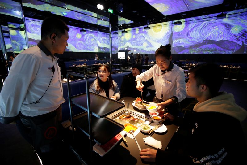 &copy; Reuters. FILE PHOTO: A waiter serves diners at a Haidilao's new artificial intelligence hotpot restaurant in Beijing, China, November 14, 2018. REUTERS/Jason Lee/File photo