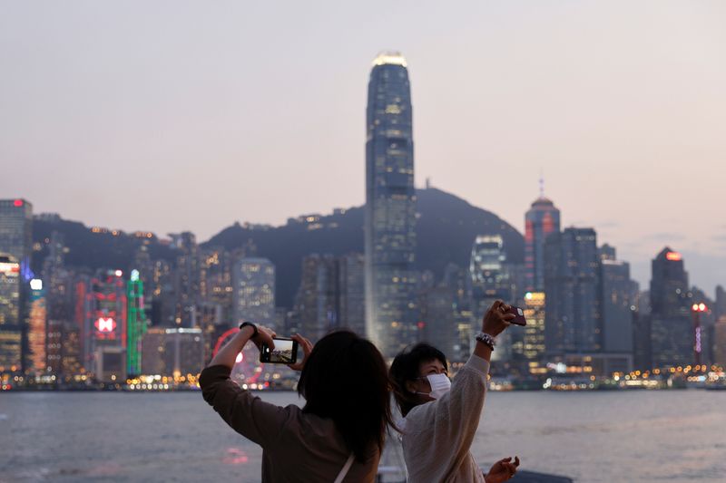 © Reuters. FILE PHOTO: People take photos of the skyline during sunset with the Central financial district in the background, in Hong Kong, China March 11, 2021. REUTERS/Tyrone Siu/File photo