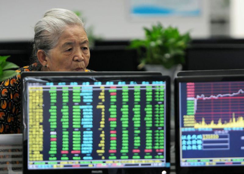 &copy; Reuters. FILE PHOTO: A woman looks at monitors showing stock information at a brokerage house in Jiujiang, Jiangxi province, China June 19, 2018.  REUTERS/Stringer/File photo