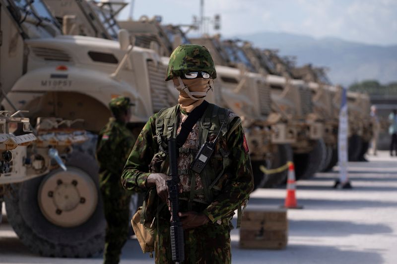 © Reuters. FILE PHOTO: A Kenyan police officer stands next to a row of anti-mine armoured vehicles in Port-au-Prince, Haiti, on July 22, 2024.  Roberto Schmidt/Pool via REUTERS/File Photo