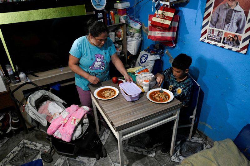 &copy; Reuters. Lilian Gonzalez, 36, prepares a meal with the food she received from a soup kitchen, with her son, Joaquin Mendieta, 11, and her daughter, Dana Mendieta, in Villa Soldati, on the outskirts of Buenos Aires, Argentina, September 16, 2024. REUTERS/Mariana Ne