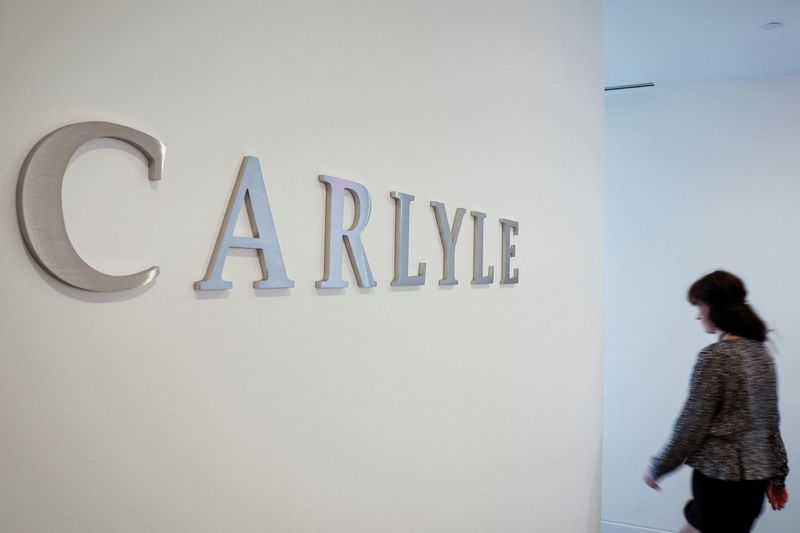 &copy; Reuters. A woman walks next to the logo for Carlyle at the company’s offices in New York City, U.S., June 28, 2022. Picture taken June 28, 2022. REUTERS/Brendan McDermid/File Photo