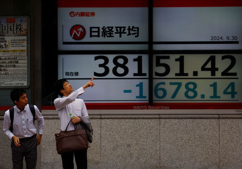 © Reuters. Passersby chat in front of an electric board displaying the Nikkei stock average outside a brokerage in Tokyo, Japan, September 30, 2024. REUTERS/Kim Kyung-Hoon