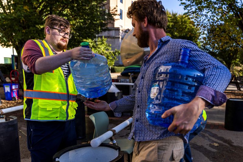 © Reuters. A worker help a resident to collect water from a truck following the passing of Hurricane Helene, in Asheville, North Carolina, U.S., October 2, 2024.  REUTERS/Eduardo Munoz