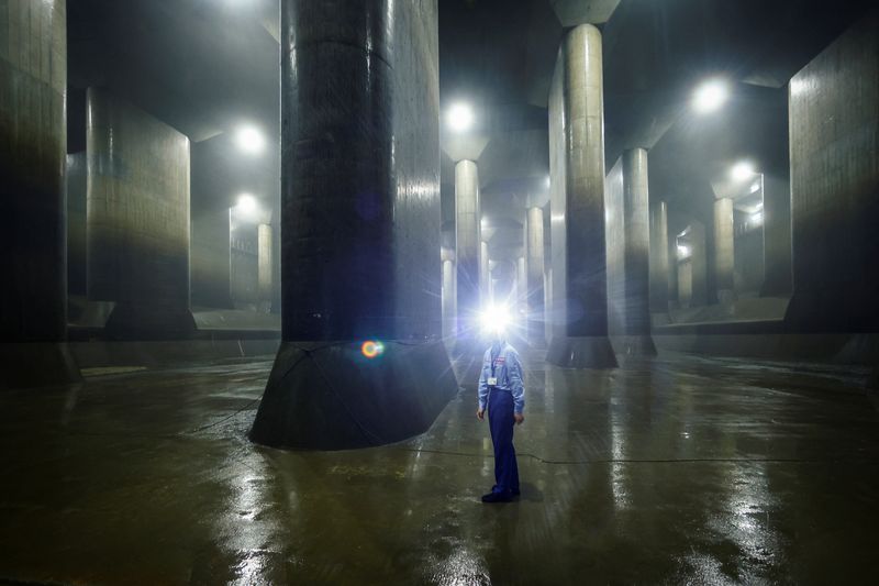 &copy; Reuters. A staff member of Metropolitan Outer Floodway Management Office demonstrates how to perform check-ups inside a pressure-adjusting water tank, part of a complex of underground water discharge tunnels constructed to protect Tokyo and its suburbs against flo