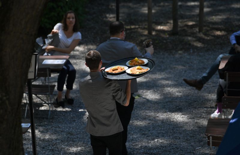 &copy; Reuters. FILE PHOTO: A waiter carries food at the beer garden of the Park Cafe, after its re-opening, amid the spread of the coronavirus disease (COVID-19) in Munich, Germany, May 18, 2020. REUTERS/Andreas Gebert/File photo