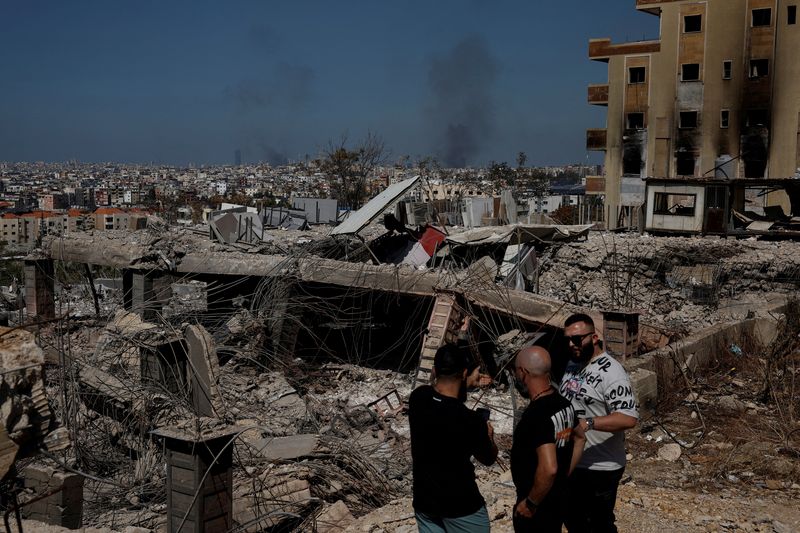 &copy; Reuters. FILE PHOTO: People stand amid damage caused by Israeli airstrikes, as smoke rises over Beirut southern suburbs, amid ongoing hostilities between Hezbollah and Israeli forces, in the Choueifat district, in Beirut, Lebanon, October 3, 2024. REUTERS/Louisa G