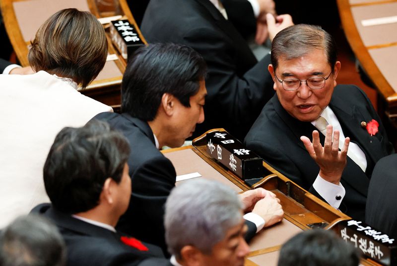 © Reuters. Japan's new Prime Minister Shigeru Ishiba talks to ministers ahead of giving his first policy speech at the upper house of the parliament in Tokyo, Japan, October 4, 2024. REUTERS/Kim Kyung-Hoon