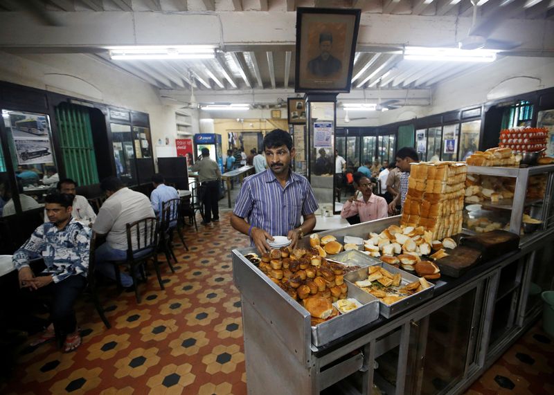 © Reuters. FILE PHOTO: A waiter arranges plates at a counter stacked with breakfast items at an Iranian Parsi restaurant in Mumbai, India, July 20, 2018. REUTERS/Francis Mascarenhas/File Photo