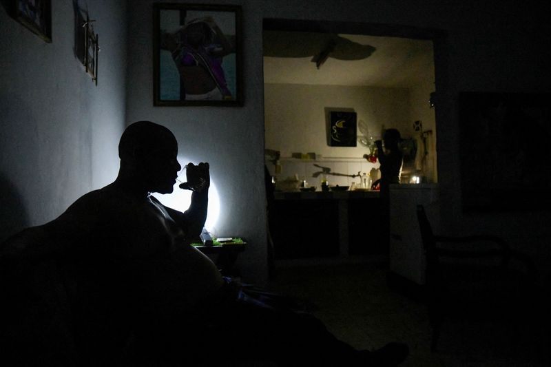 © Reuters. FILE PHOTO: A man drinks water at his home during a power outage caused by breakdowns forcing six plants to go off-line on the grid, according to the state run power company, in Matanzas, Cuba August 22, 2024. REUTERS/Norlys Perez/File Photo