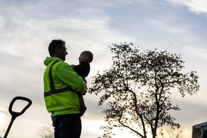 © Reuters. FILE PHOTO: A man from Venezuela holds his son after returning home from a day of work at a construction site in Columbus, Ohio, U.S., March 25, 2024. REUTERS/Carlos Barria/File Photo