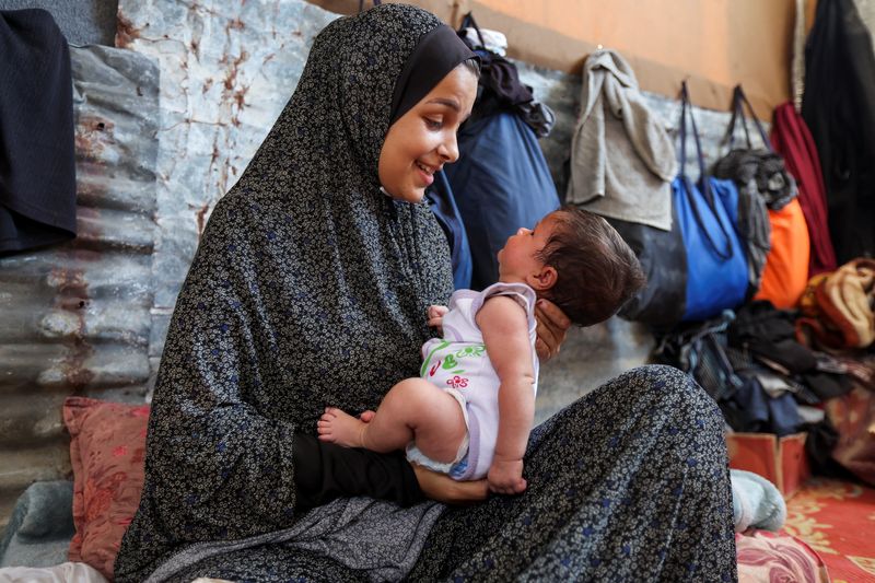 &copy; Reuters. FILE PHOTO: Displaced Palestinian mother Rana Salah holds her daughter Milana in a tent where they shelter, amid the Israel-Hamas conflict, in Deir Al-Balah in the central Gaza Strip, September 10, 2024. REUTERS/Ramadan Abed/File Photo