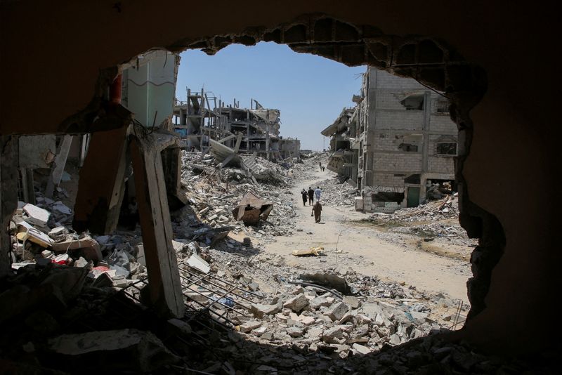 &copy; Reuters. FILE PHOTO: Palestinians walk past the rubble of houses destroyed during the Israeli military offensive, amid Israel-Hamas conflict, in Khan Younis in the southern Gaza Strip July 10, 2024. REUTERS/Hatem Khaled/File Photo