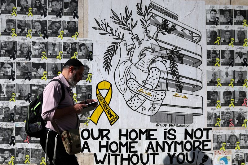 © Reuters. FILE PHOTO: A man walks next to memorial pictures of hostages, most of whom were kidnapped during the deadly October 7 attack by Hamas, in Tel Aviv, Israel, September 4, 2024. REUTERS/Florion Goga/File Photo