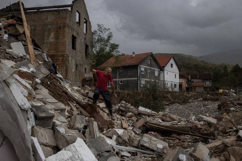 © Reuters. A man walks over a destroyed house after floods and landslides in a village of Trusina, Bosnia and Herzegovina, October 6, 2024. REUTERS/Marko Djurica