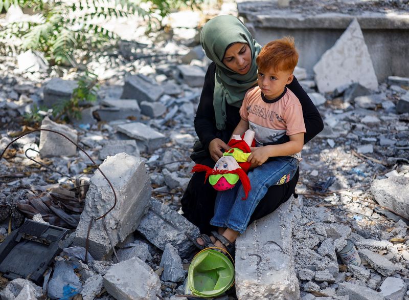 &copy; Reuters. Palestinian woman Inas Abu Maamar, who was photographed at Nasser hospital morgue on October 17 cradling the body of her five-year-old niece Saly, killed in an Israeli strike, sits with her nephew Ahmed, Saly's brother, as they visit a damaged cemetery wh