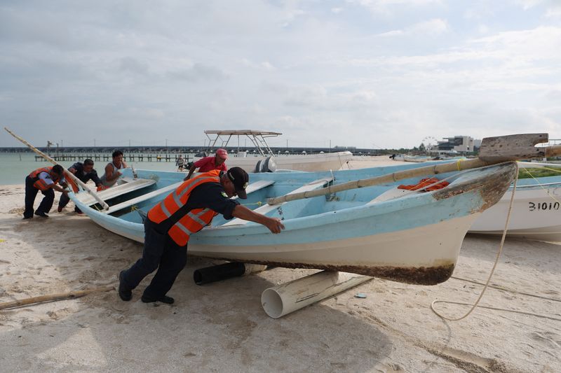 © Reuters. People move a fishing boat away from the water as Hurricane Milton advances, in Progreso, Mexico, October 7, 2024. REUTERS/Lorenzo Hernandez