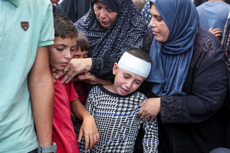 &copy; Reuters. Un bambino reagisce mentre le persone si radunano accanto ai corpi dei palestinesi uccisi da attacchi israeliani, nel corso del conflitto tra Israele e Hamas, presso l'Ospedale dei Martiri di Al-Aqsa a Deir Al-Balah, nella Striscia di Gaza centrale, l'8 o