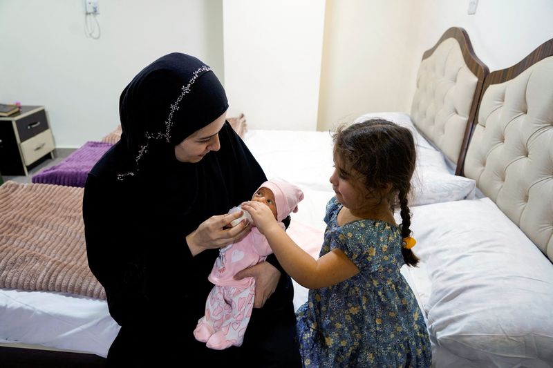 © Reuters. Lubana Ismail, a displaced Lebanese woman who fled from her home in Tyre due to Israeli bombardments in Southern Lebanon, holds her newborn baby girl, Zahraa, to whom she gave birth in Iraq, at a hotel in Najaf, Iraq, October 7, 2024. REUTERS/Ahmed Saeed