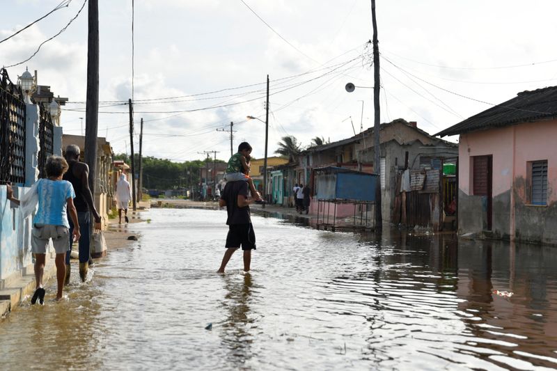 &copy; Reuters. FILE PHOTO: A man carries a child through a flooded street as Hurricane Milton approaches the Cuban coast in Batabano, Cuba, October 8, 2024. REUTERS/Norlys Perez/File Photo