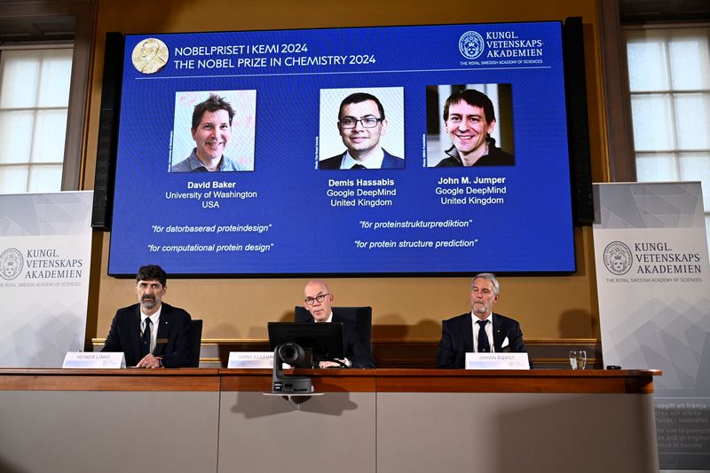 © Reuters. Announcers of the laureates for the Nobel Prize in Chemistry, Johan Aqvist, Hans Ellegren and Heiner Linke, look on as the images of the winners, David Baker (University of Washington, USA), Demis Hassabis (Google DeepMind, UK) and John M Jumper (Google DeepMind, UK) are displayed, in Stockholm, Sweden October 9, 2024. TT News Agency/Christine Olsson via REUTERS