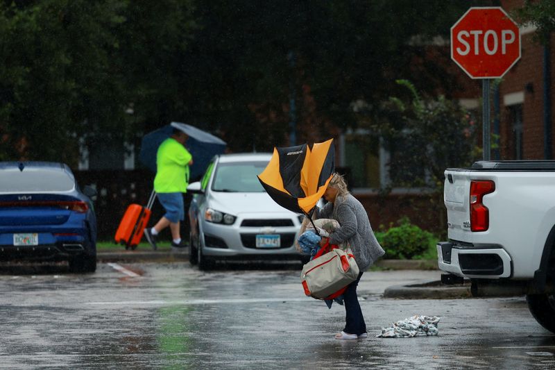 © Reuters. A woman holds an umbrella while arriving at a shelter as Hurricane Milton approaches, in Lakeland, Florida, U.S., October 9, 2024.  REUTERS/Jose Luis Gonzalez