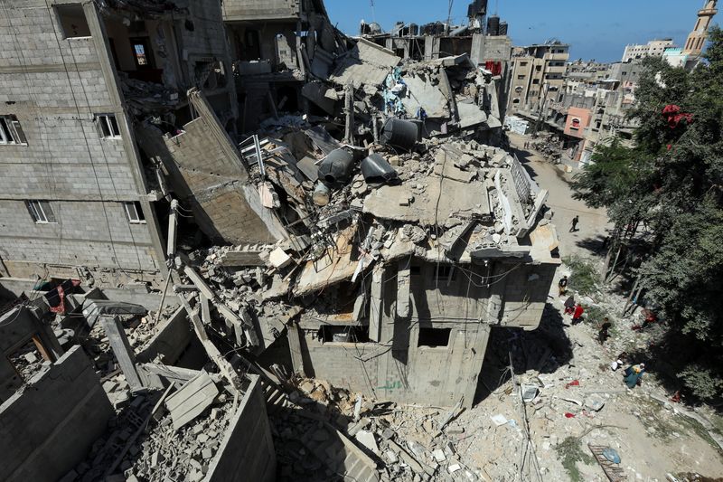 &copy; Reuters. Palestinians walk past a house hit in an Israeli strike, amid the Israel-Hamas conflict, in Bureij refugee camp, in the central Gaza Strip, October 8, 2024. REUTERS/Ramadan Abed/File Photo