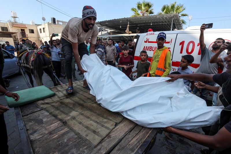 &copy; Reuters. A Palestinian carries a body at Al-Aqsa Martyrs Hospital, in the aftermath of an Israeli strike on a school sheltering displaced people, amid the Israel-Hamas conflict, in Deir Al-Balah, central Gaza Strip, October 10, 2024. REUTERS/Ramadan Abed