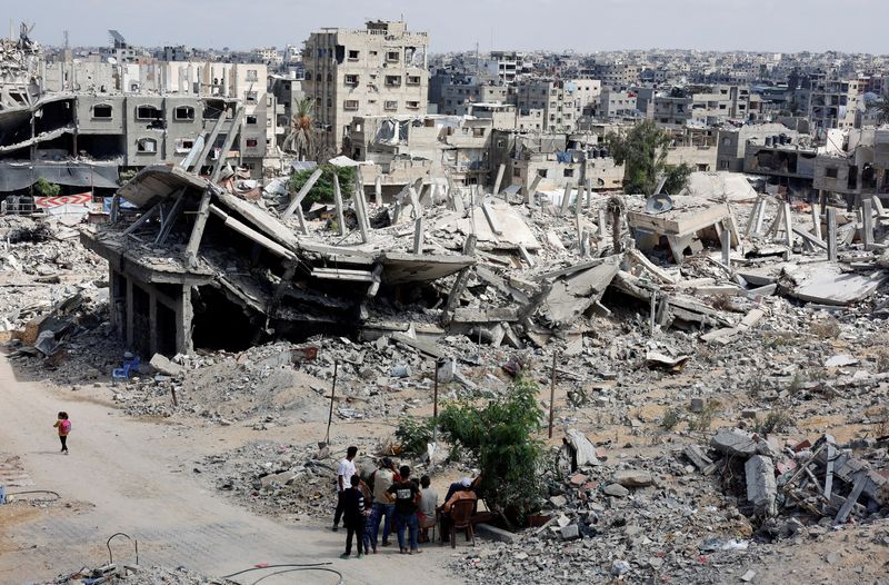 &copy; Reuters. FILE PHOTO: Palestinians sit next to the rubble of houses destroyed in Israel's military offensive, amid the ongoing conflict between Israel and Hamas, in Khan Younis in the southern Gaza Strip October 7, 2024. REUTERS/Mohammed Salem/File Photo