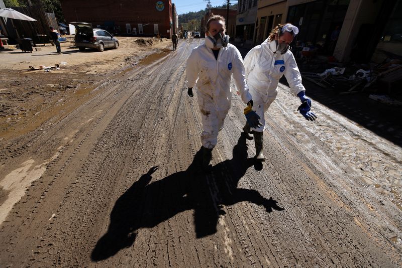 © Reuters. Volunteers wear personal protective equipment as they make their way down Main Street towards their next destination to help clean downtown businesses after severe flooding from Hurricane Helene, in Marshall, North Carolina, U.S. October 10, 2024. REUTERS/Jonathan Drake