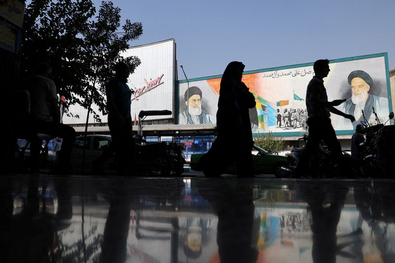 &copy; Reuters. FILE PHOTO: People walk past a mural depicting the late leader of the Islamic Revolution Ayatollah Ruhollah Khomeini and Iran's Supreme Leader Ayatollah Ali Khamenei on a building in a street in Tehran, Iran, October 7, 2024. Majid Asgaripour/WANA (West A