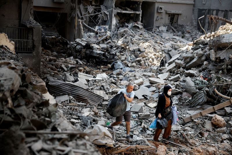 © Reuters. People walk at the site of an Israeli air strike, amid ongoing hostilities between Hezbollah and Israeli forces, in Beirut, Lebanon, October 11, 2024. REUTERS/Louisa Gouliamaki