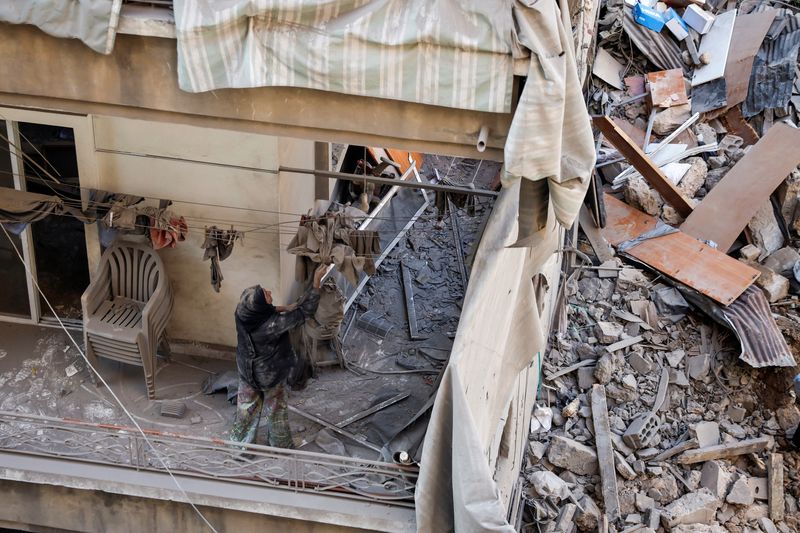 &copy; Reuters. Maha Haddad, mother-in-law of Ahmed Al-Khatib cleans rubble in their damaged apartment at the strike site in Beirut, Lebanon, October 11, 2024. REUTERS/Louisa Gouliamaki