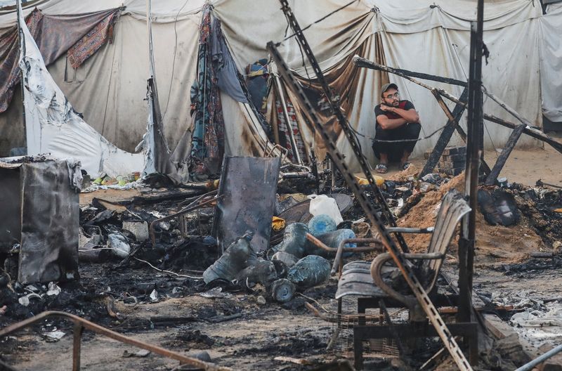 © Reuters. A Palestinian man looks on next to the damage at the site of an Israeli strike on tents sheltering displaced people, amid the Israel-Hamas conflict, at Al-Aqsa Martyrs hospital in Deir Al-Balah in the central Gaza Strip, October 14, 2024. REUTERS/Ramadan Abed 