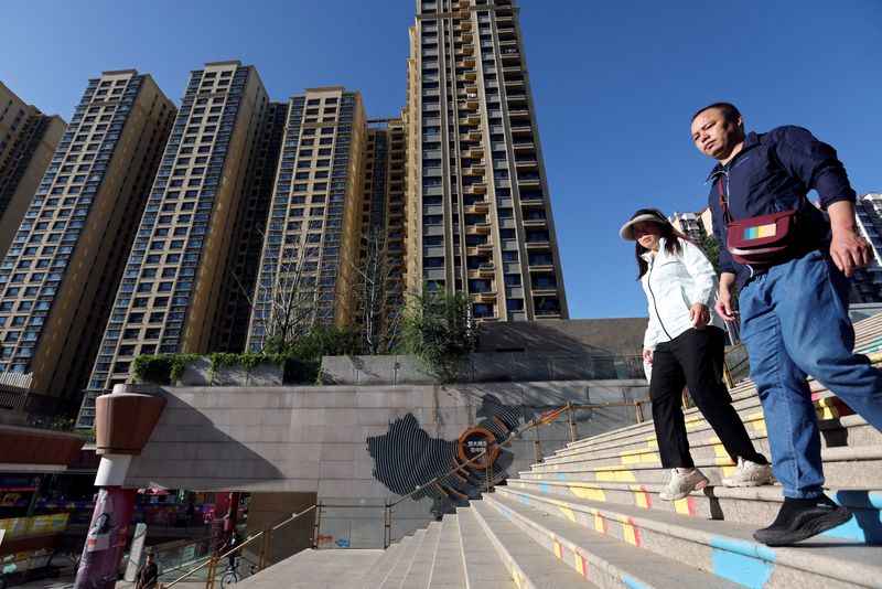 © Reuters. FILE PHOTO: People walk past residential buildings next to the Evergrande City Plaza in Beijing, China September 27, 2023. REUTERS/Florence Lo/File Photo