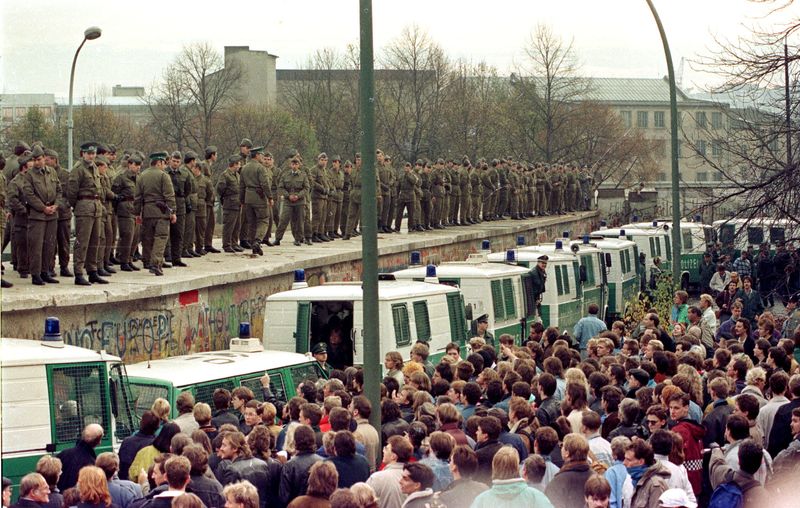 © Reuters. FILE PHOTO: Hundreds of East Berlin border guards stand atop the Berlin Wall at the Brandeburg Gate faced by thousands of West Berliners on November 11, 1989/File Photo