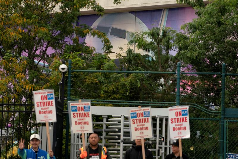 © Reuters. FILE PHOTO: The image of a Boeing 737 jetliner is seen behind Boeing factory workers and supporters as they gather on a picket line near the entrance to a Boeing production facility in Renton, Washington, U.S. September 15, 2024.  REUTERS/David Ryder/File Photo