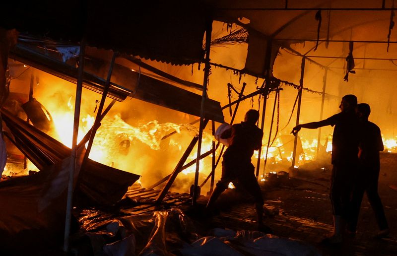 &copy; Reuters. Pessoas tentam apagar incêndio causada por ataque de Israek na região central da Faixa de Gazan14/10/2024 REUTERS/Ramadan Abed