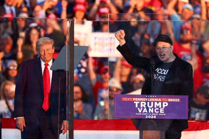 © Reuters. FILE PHOTO: Tesla CEO and X owner Elon Musk speaks as Republican presidential nominee and former U.S. president Donald Trump looks on during a rally at the site of the July assassination attempt against Trump, in Butler, Pennsylvania, U.S., October 5, 2024. REUTERS/Carlos Barria/File Photo