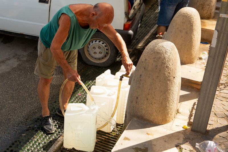 © Reuters. FILE PHOTO: A man fills containers with water amidst water shortages in Sicilan town of Alcamo, Italy, August 8, 2024. REUTERS/Antonio Cascio/File Photo