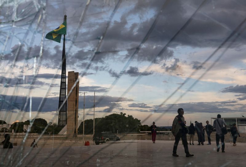 © Reuters. FILE PHOTO: A Brazilian flag waves as seen behind broken glass at the Supreme Court building, following Brazil's anti-democratic riots, in Brasilia, Brazil, January 10, 2023. REUTERS/Ricardo Moraes/File Photo