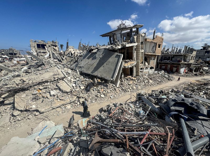 © Reuters. FILE PHOTO: Palestinians walk near rubble and destroyed buildings, amid the Israel-Hamas conflict, in Khan Younis, in the southern Gaza Strip, October 10, 2024. REUTERS/Mohammed Salem/File Photo